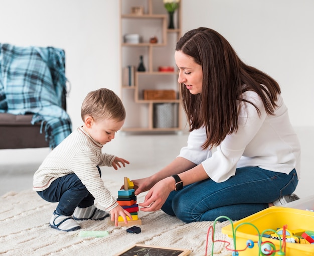 Vista laterale della mamma e del bambino che giocano con i giocattoli