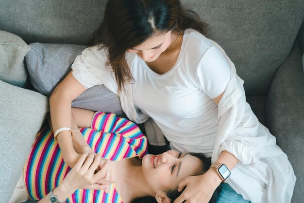 Photo side view of mother and daughter sitting on sofa at home