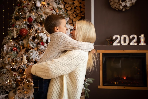 Side view of mother embracing son against christmas tree at home