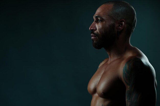 Photo side view of muscular man against black background