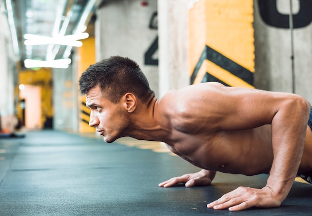 Side view of a muscular young man doing push ups