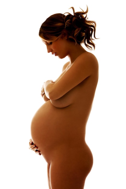 Side view of naked pregnant woman smiling while standing over white background