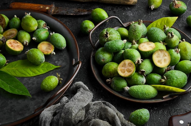 Side view of natural fresh green feijoas on a black stone background