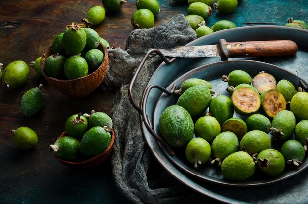 Side view of natural fresh green feijoas on a black stone background