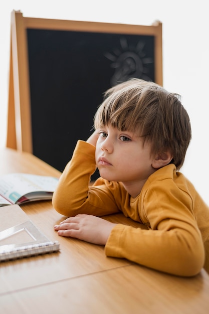 写真 ノートと黒板を机に退屈した子供の側面図