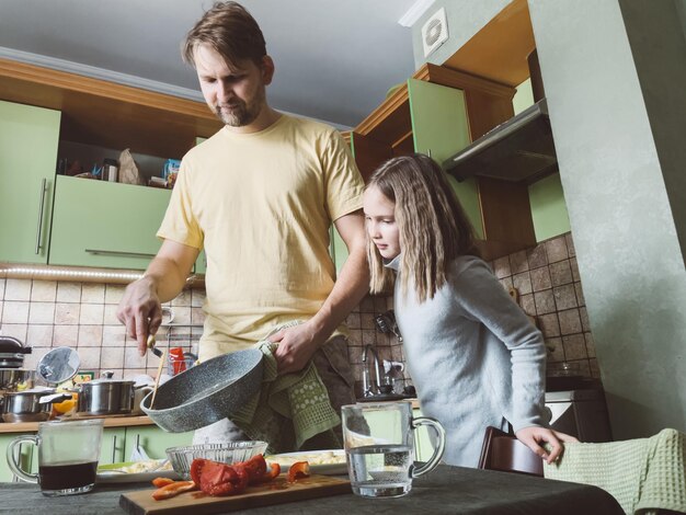 Фото Боковой вид отца и дочери, готовящих завтрак дома