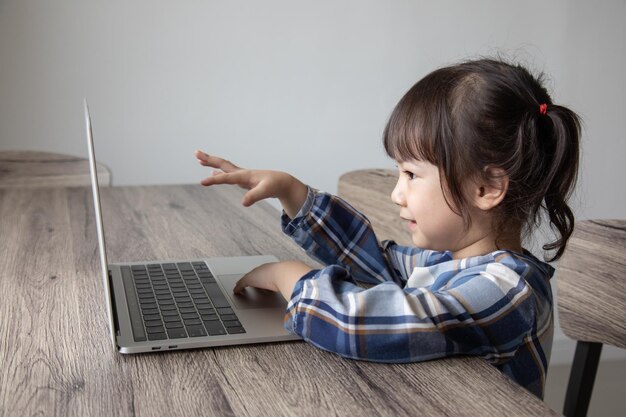 写真 テーブルでラップトップを使用している女の子のサイドビュー