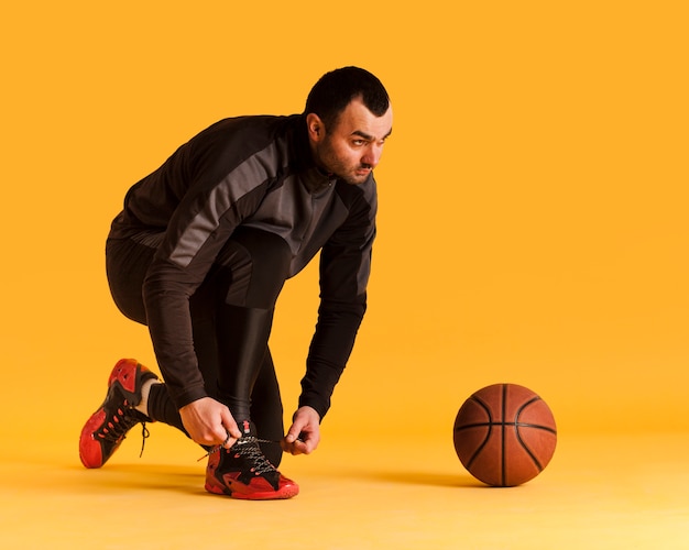 写真 靴ひもを結ぶボールとコピースペースの男性のバスケットボール選手の側面図