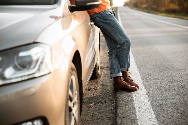 写真 ロードトリップ中に車にもたれて男の側面図