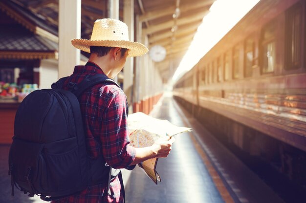 写真 鉄道駅に立って地図を読んでいる男のサイドビュー