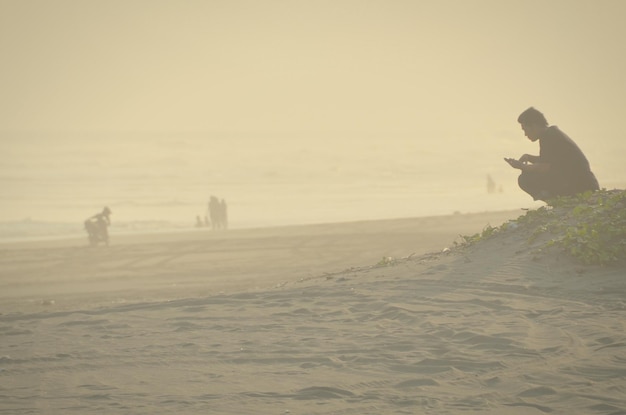 Фото Боковой вид человека, сидящего на пляже