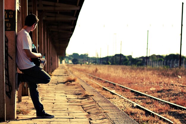 写真 古い鉄道駅に立っている男の横の景色