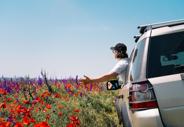 Фото Боковой вид человека, управляющего машиной, на цветущих диких растениях на поле против неба летом