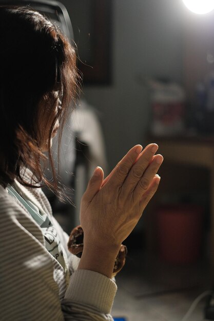 写真 家で祈っている年配の女性の横の景色