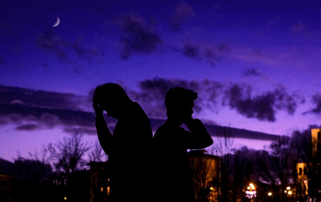 Фото Боковой вид силуэта людей, стоящих на драматическом небе во время сумерек
