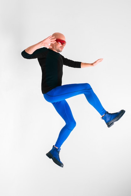 Фото Вид сбоку стильного человека в футуристических красных очках и синих колготках, лежащих в воздухе