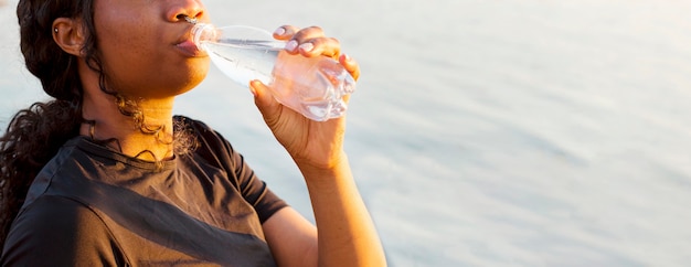 写真 コピースペースと湖のほとりで水を飲む女性の側面図