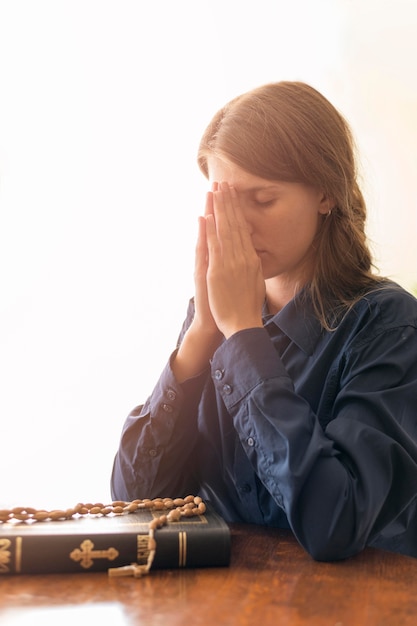 写真 神聖な本とロザリオで祈る女性の側面図