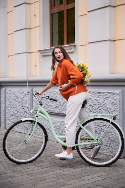 사진 꽃의 부케와 함께 야외에서 그녀의 자전거를 타는 여자의 모습
