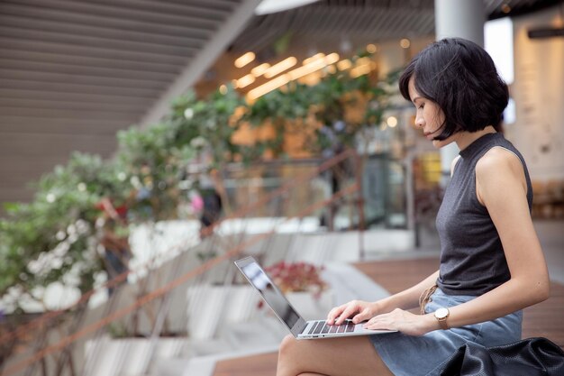 写真 階段に座っている女性がラップトップを使っている横の景色