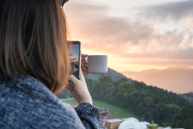 写真 夕暮れの空に向かって携帯電話を使っている女性のサイドビュー