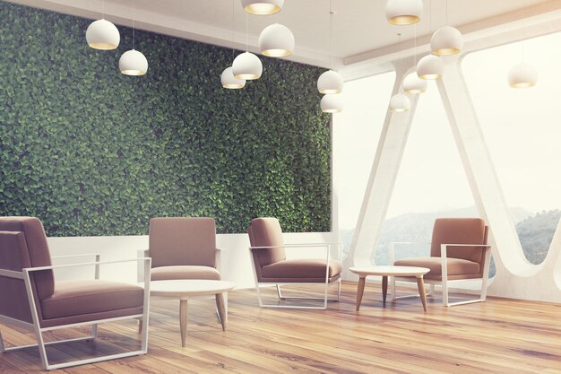 Photo side view of an office cafe interior with a large grass wall, panoramic windows with triangular frames, white round tables and soft brown chairs near them. 3d rendering mock up toned image