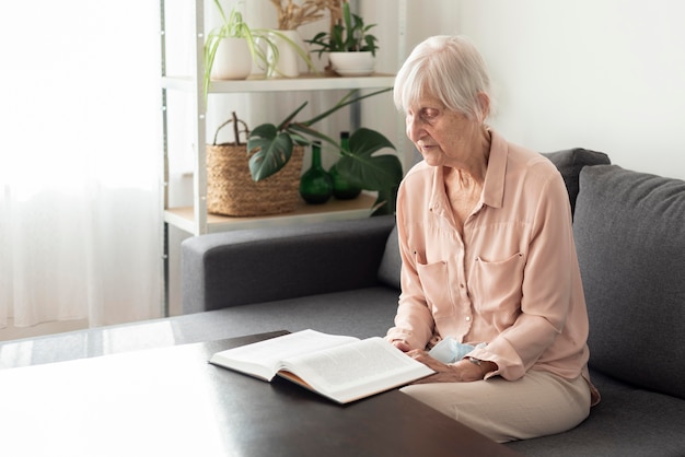 Photo side view of older woman in nursing home reading a book