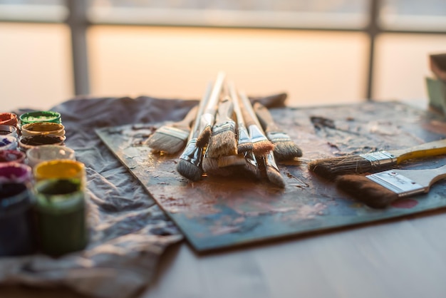 Side view of pallet with oil paint brushstrokes under paintbrush set in an art studio