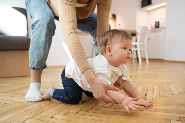 Side view parent helping baby crawl