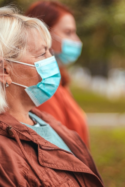 Вид сбоку на людей в защитных медицинских масках на улице во время пандемии коронавируса, гриппа или премониума. Социальное дистанцирование