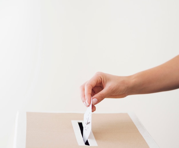 Photo side view person putting ballot in box