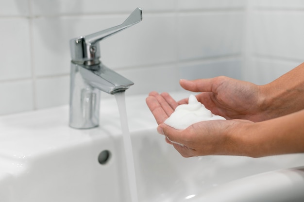 Photo side view person washing hands with soap