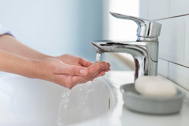 Вид сбоку лица, моющего руки водой