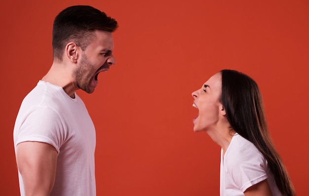 Side view photo of young angry and shouting couple in white t-shirts