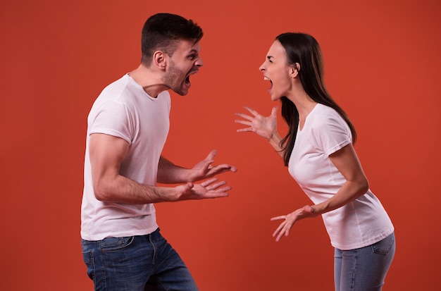 Photo side view photo of young angry and shouting couple in white t-shirts