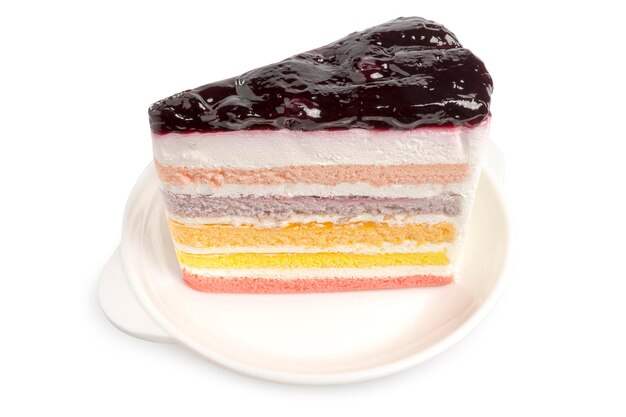 Side view of a piece of Rainbow Cake topping with blueberry sauce served on white plate