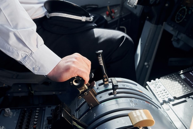 Side view Pilot in formal wear sits in the cockpit and controls airplane