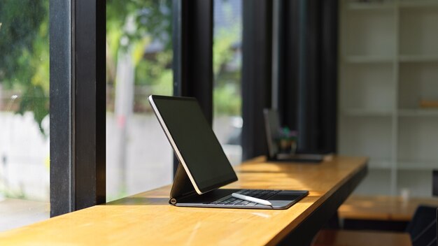 Vista laterale del tablet portatile con tastiera sul tavolo di legno al caffè