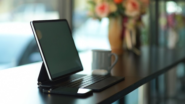 Side view of portable workspace with digital tablet and smartphone on black desk