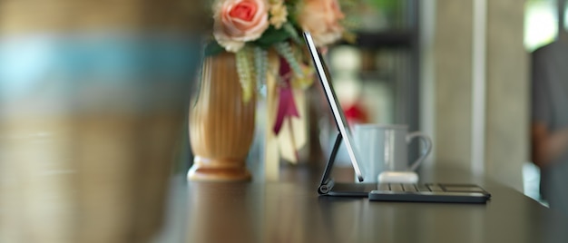 Side view of portable workspace with tablet, smartphone and flower vase decorated on the table