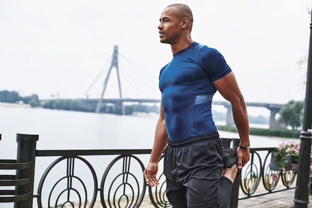 Side view portrait of an african sportive man who is stretching legs