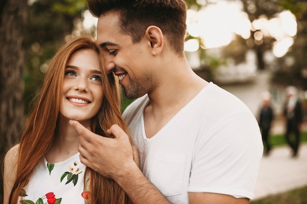 Side view portrait of a amazing couple dating outside while girl is looking away smiling while he is touching her face before kissing .