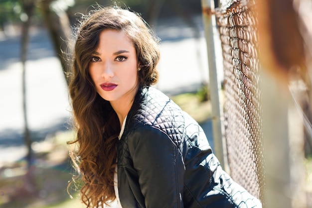 Side view portrait of beautiful woman sitting by fence