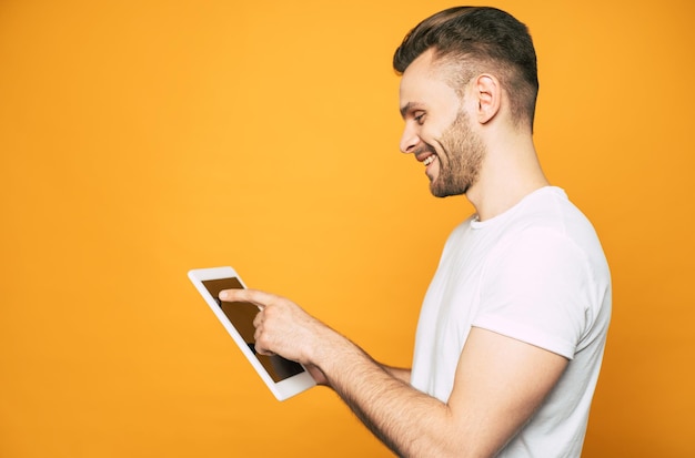 Портрет случайного делового человека с современным планшетом в руках на желтом фоне, вид сбоку