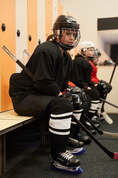 Side view portrait of female hockey team sitting in row