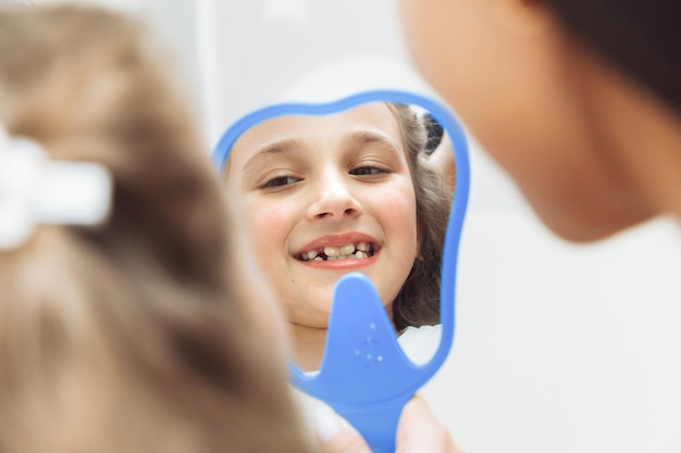 Side view portrait of little girl looking at mirror in pediatric dentistry after dental surgery