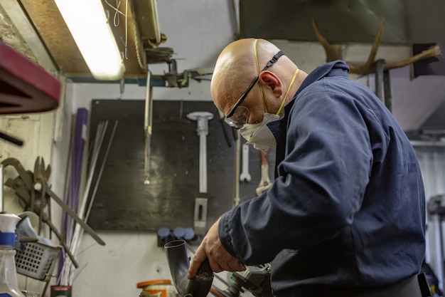 Side view portrait of man working in garage repairing motorcycle and customizing it