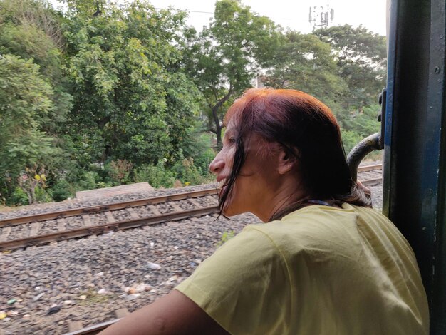 Foto ritratto laterale di una donna matura seduta su un binario ferroviario