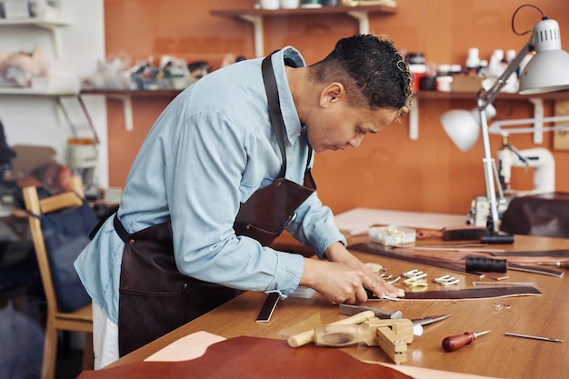 Side view portrait of modern artisan creating handmade leather belt in workshop copy space
