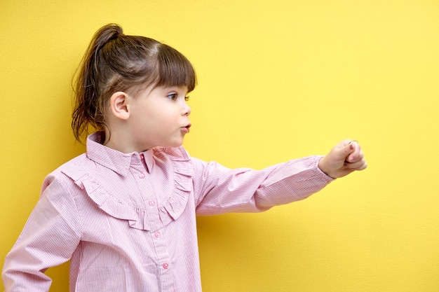 Фото Вид сбоку портрет девочки, смотрящей в сторону и говорящей рукой вперед